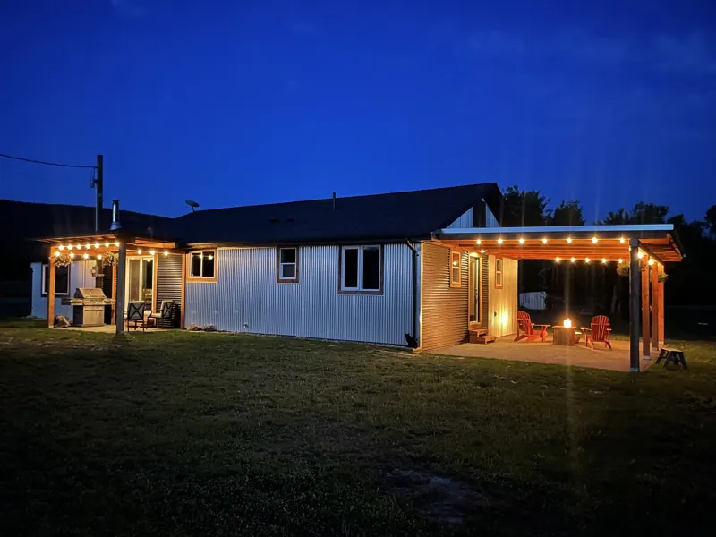 The farmhouse at blue hour, with Edison string lights and the fire pit