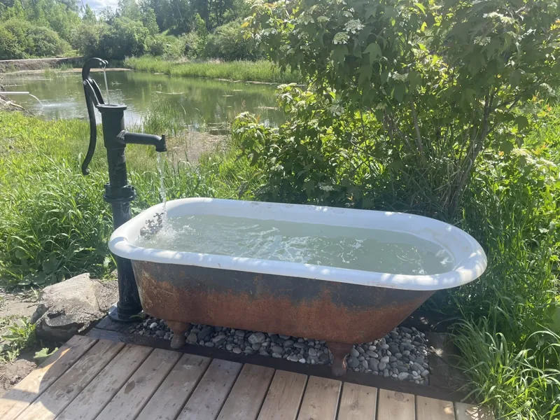 Water running through the old hand pump into the cast-iron tub